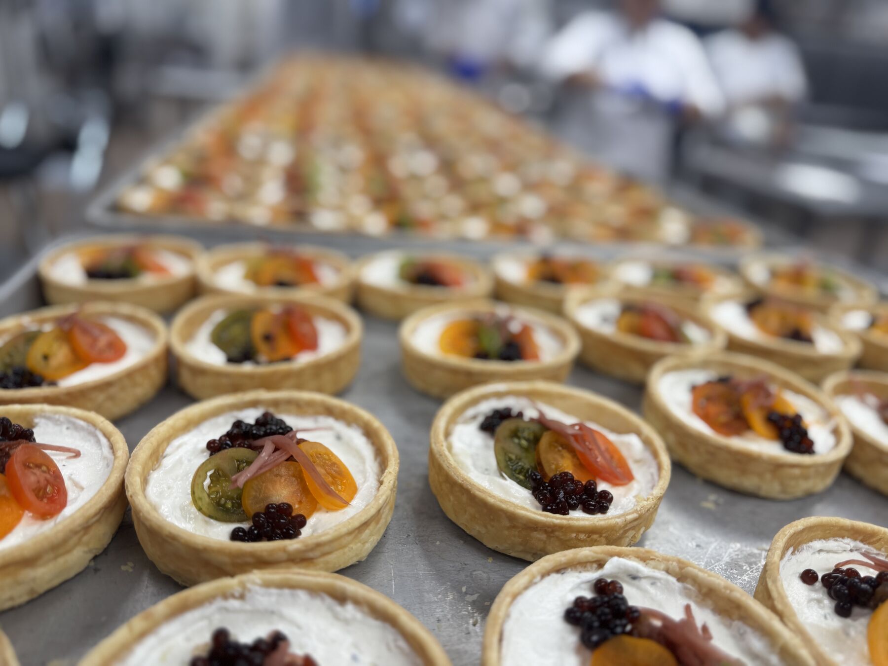 Rows of plated tarts on sheet trays in a banquet kitchen