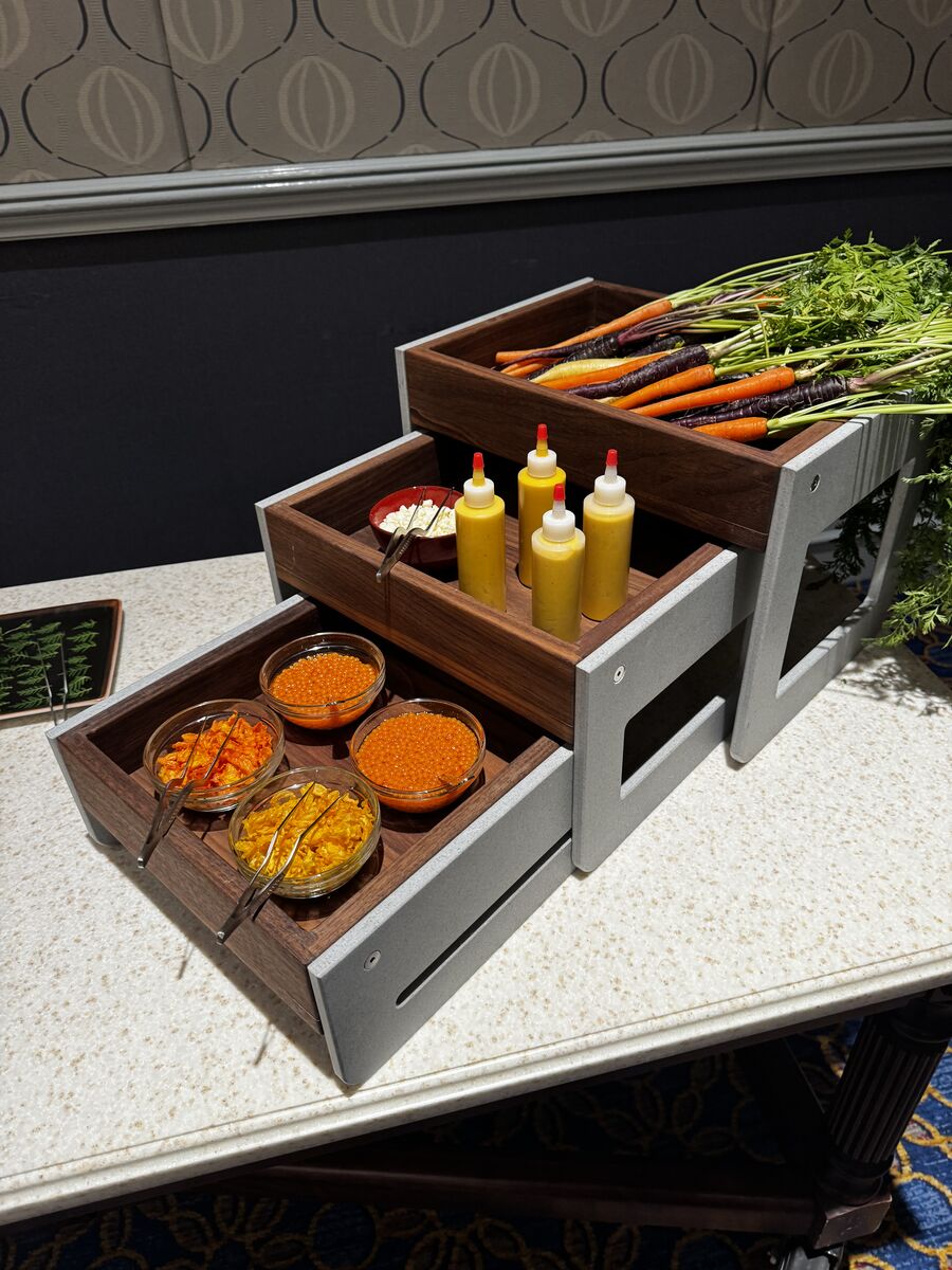 Tiered wooden station with heirloom carrots, squeeze bottles and carrot preparations